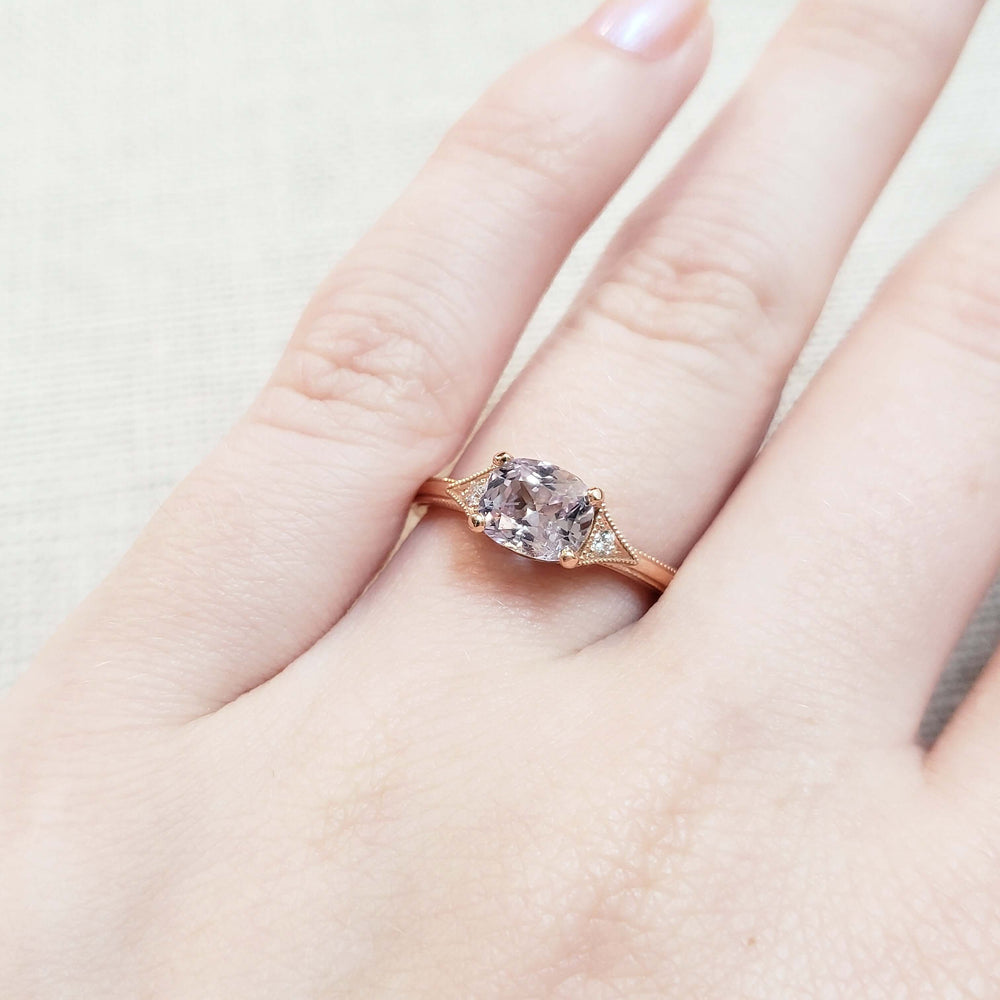 Pink sapphire and diamond rose gold ring shown on a hand