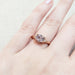 Pink sapphire and diamond rose gold ring shown on a hand