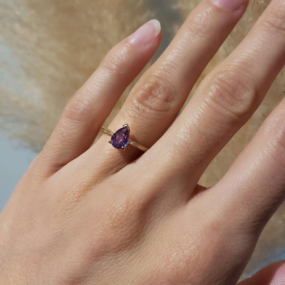 Pink sapphire yellow gold engagement ring shown on hand