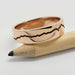 Polished 14k rose gold wedding ring with engraved mountain range, shown on a pencil