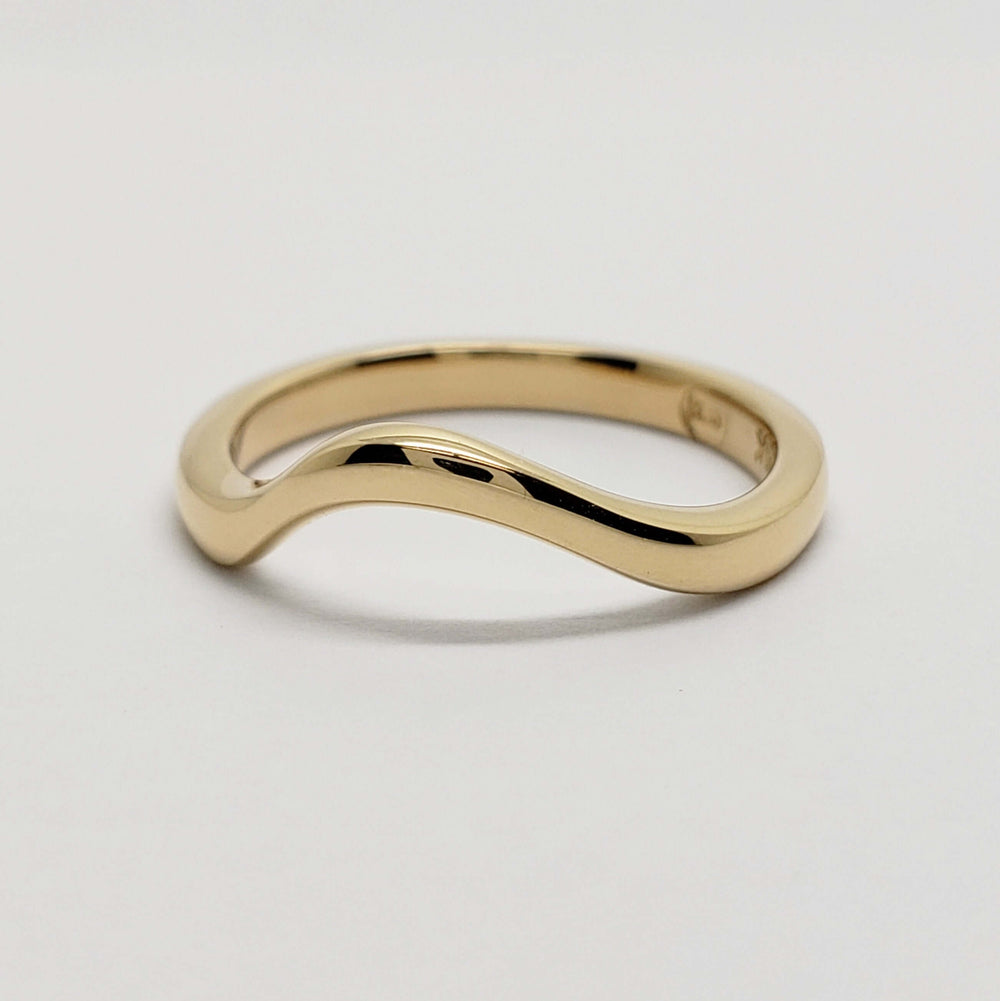 Polished 14kt yellow gold chevron wedding band on white background