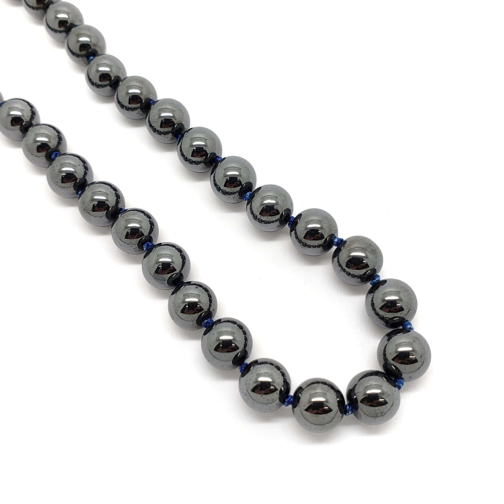 Close-up of polished hematite bead necklace strung on deep blue thread