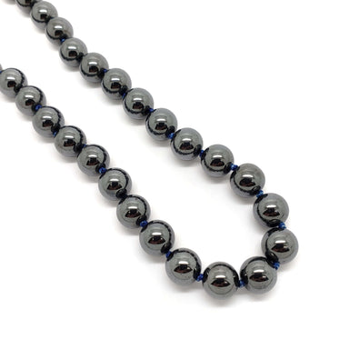 Close-up of polished hematite bead necklace strung on deep blue thread