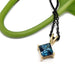 Princess cut London topaz pendant in 14kt yellow gold with black chain, beside a green stem