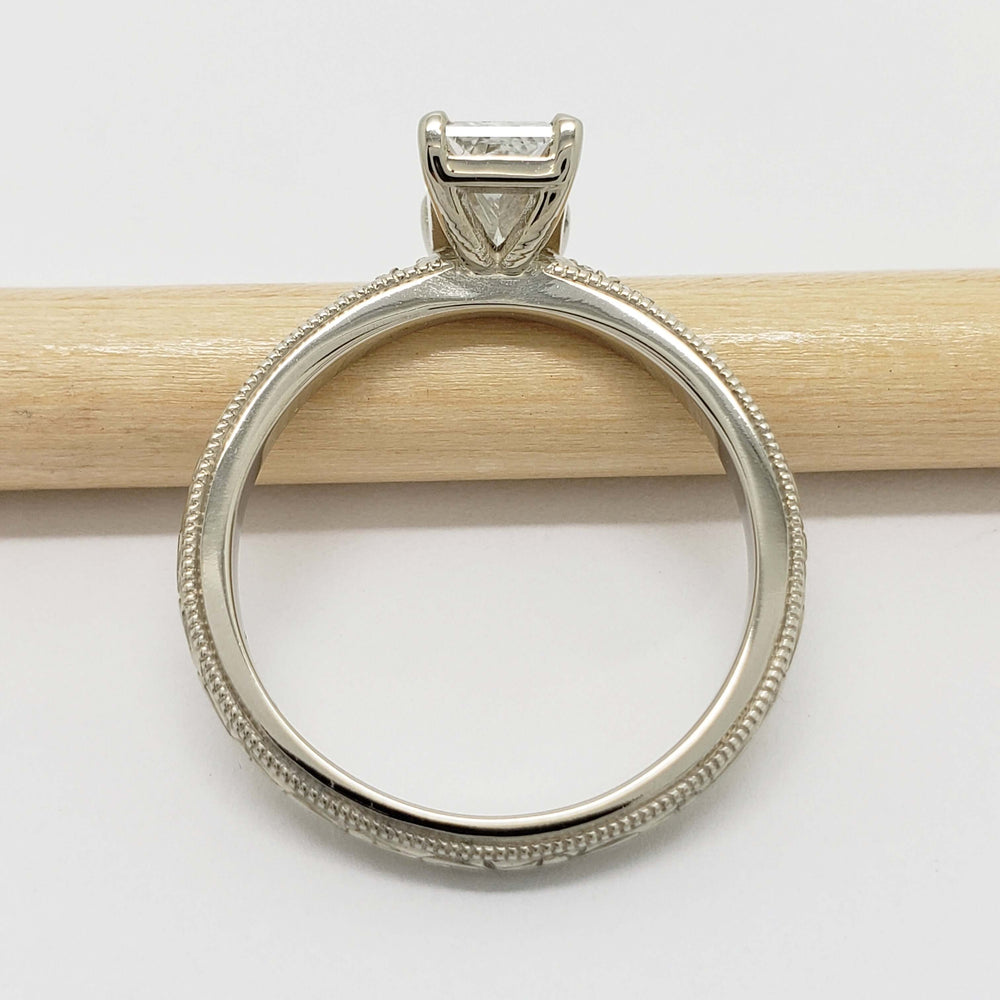 Profile of 14kt white gold engagement ring with milgrain and hand engraving, beside pencil
