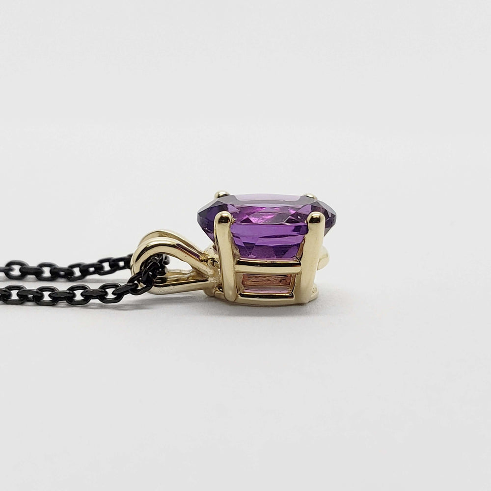 Profile view of 14kt yellow gold pendant with oval purple amethyst on black chain