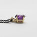 Profile view of 14kt yellow gold pendant with oval purple amethyst on black chain