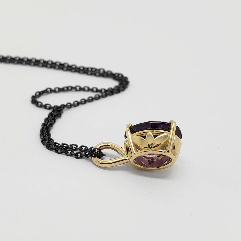 Side view of 14kt yellow gold pendant with oval lab grown purple sapphire and black chain