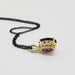 Side view of 14kt yellow gold pendant with oval lab grown purple sapphire and black chain