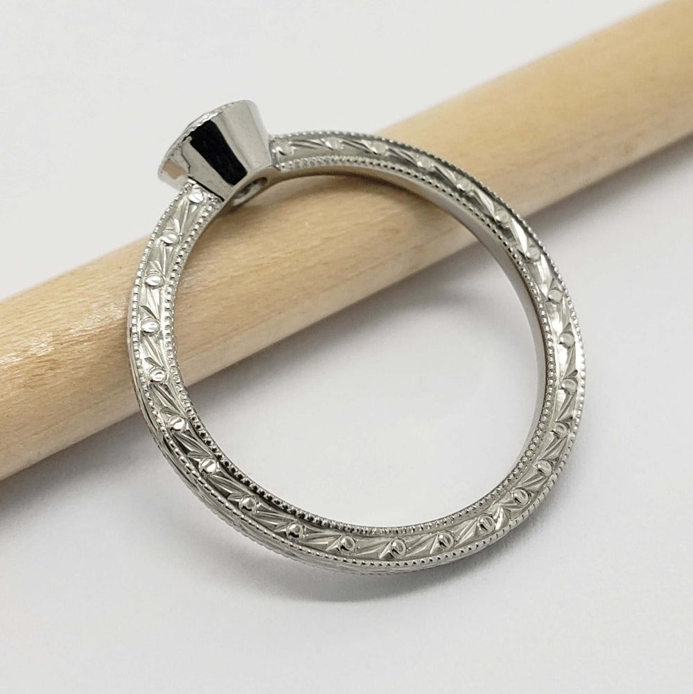 Profile view of engraved 14k white gold ring with bezel setting, no stone visible