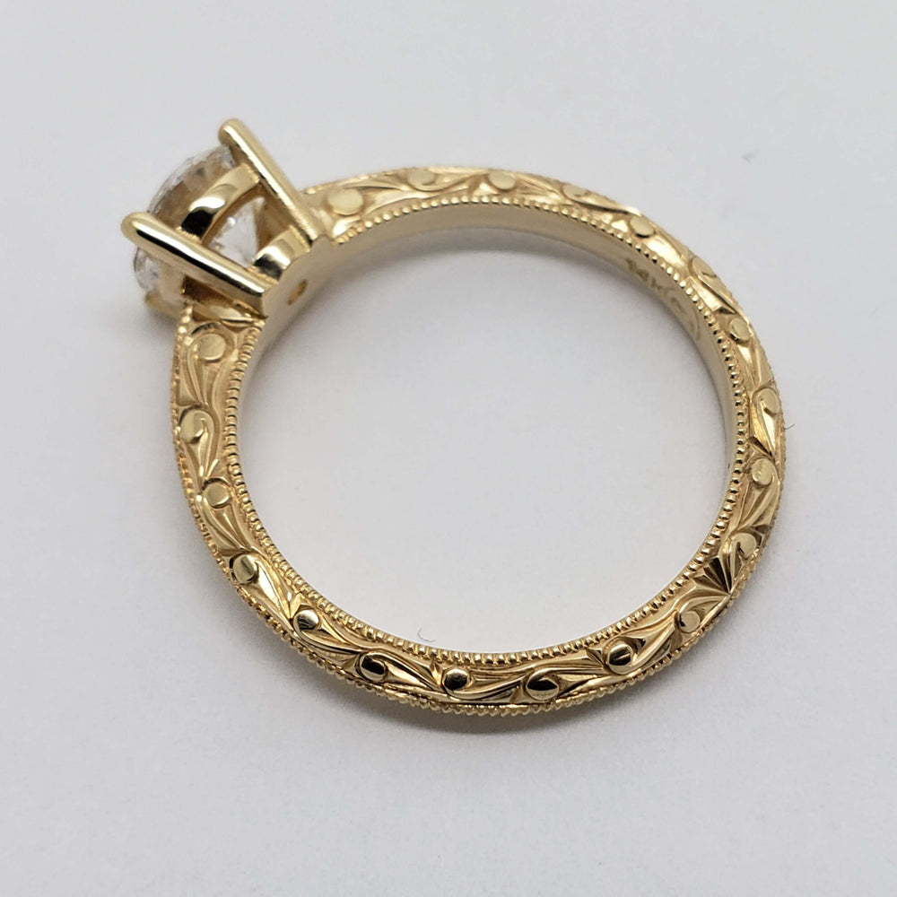 Profile of engraved 14kt yellow gold band with round lab diamond in solitaire setting