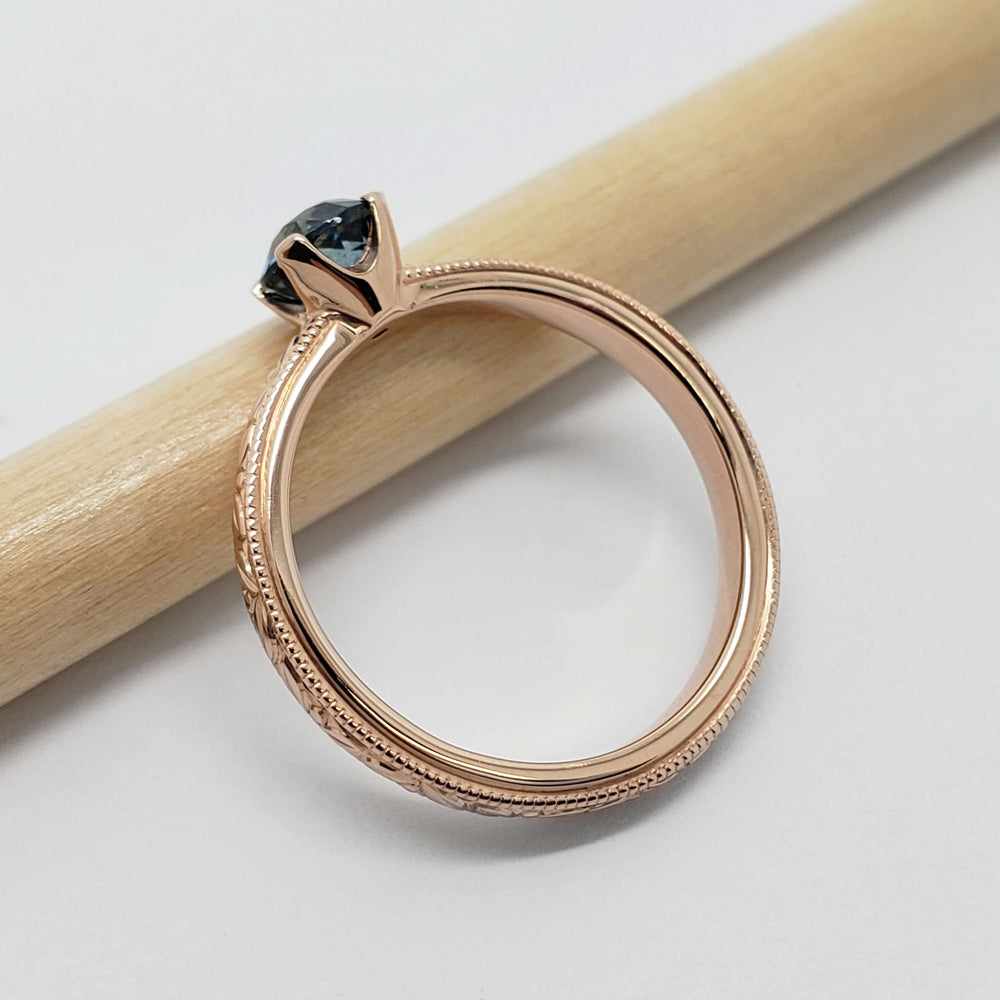 Side view of engraved rose gold ring with blue sapphire, showing millgrain detail