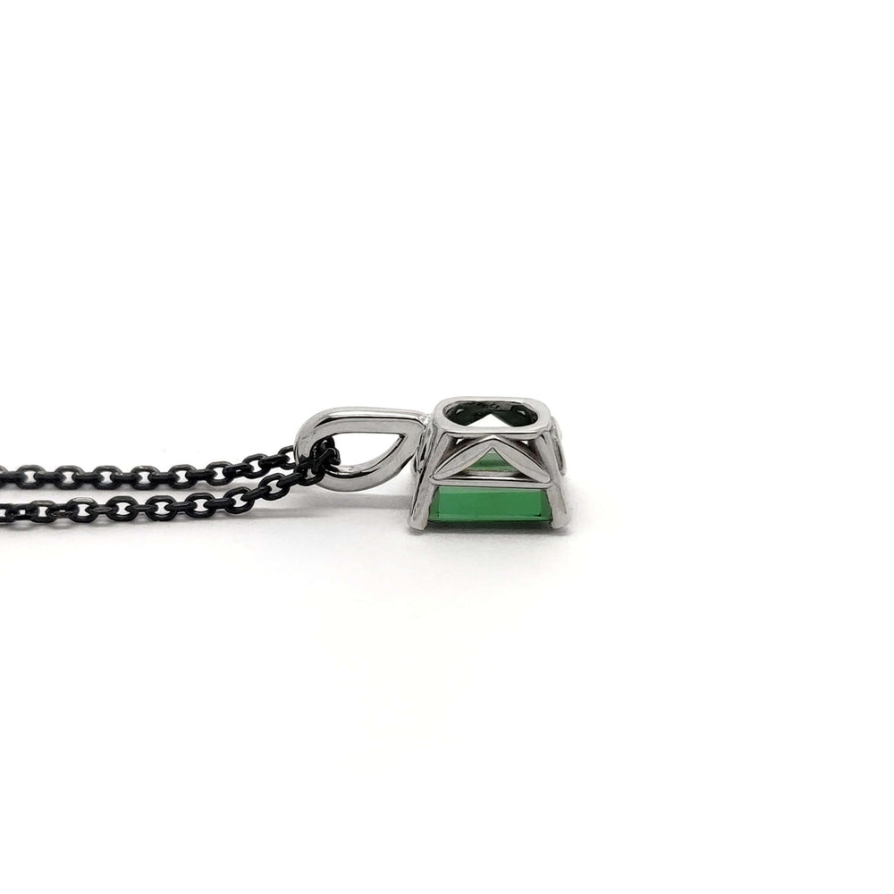 Profile view of white gold green tourmaline pendant on black chain against white background