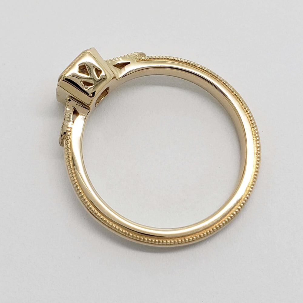 Profile of yellow gold engagement ring with millgrain and cutout details