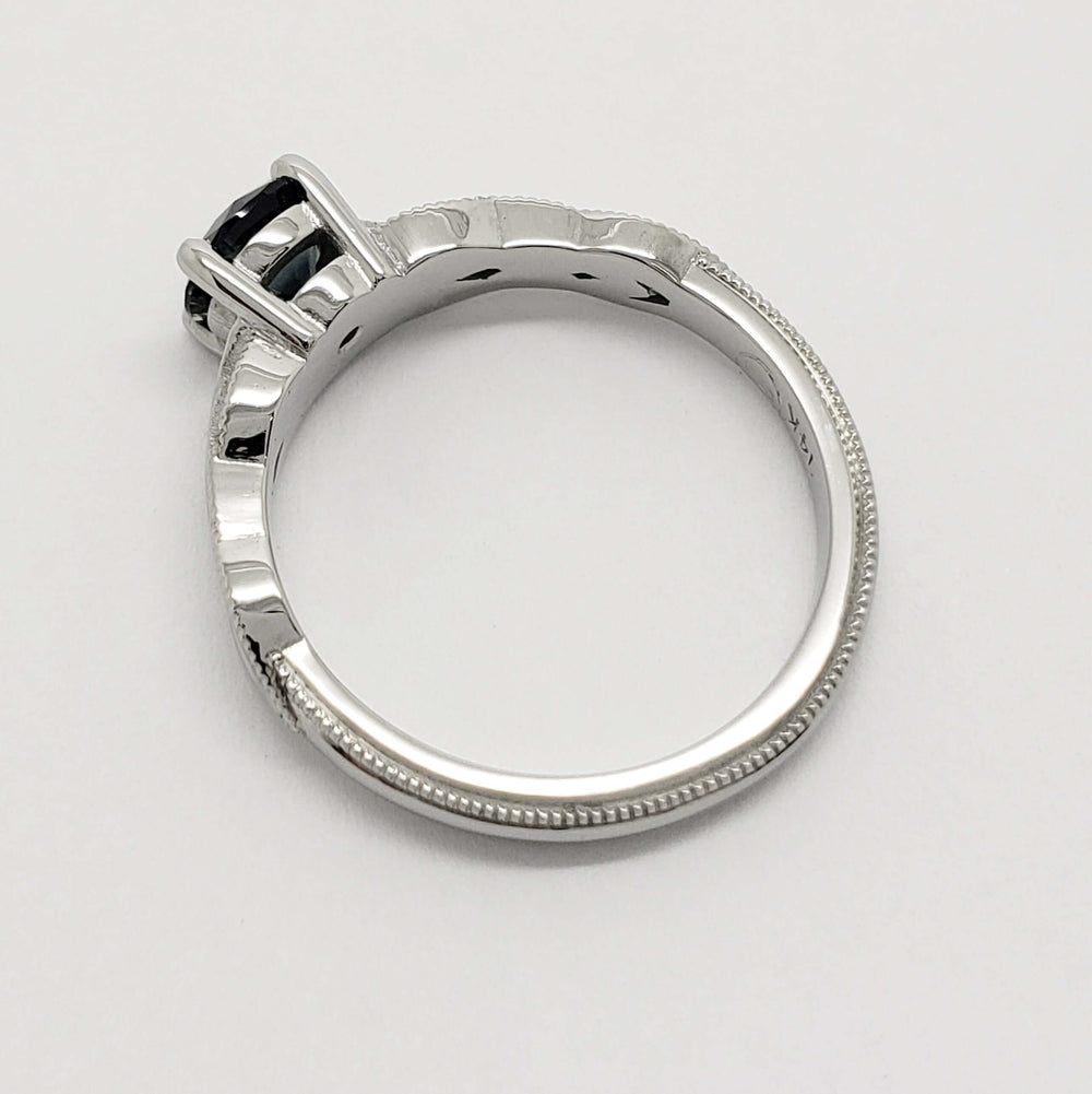 Side profile of 14kt white gold ring with millgrain detail and blue Montana sapphire
