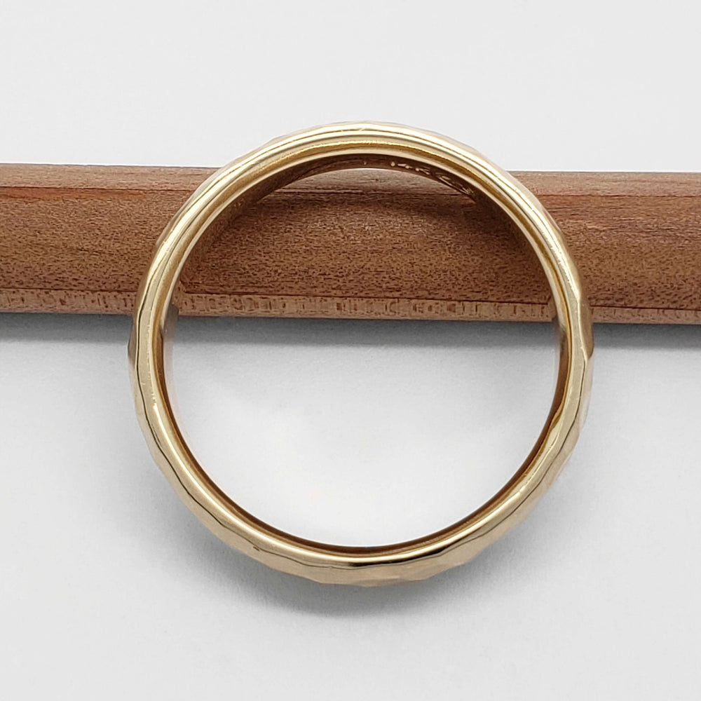 Side profile of 14kt yellow gold hammered wedding ring on a pencil