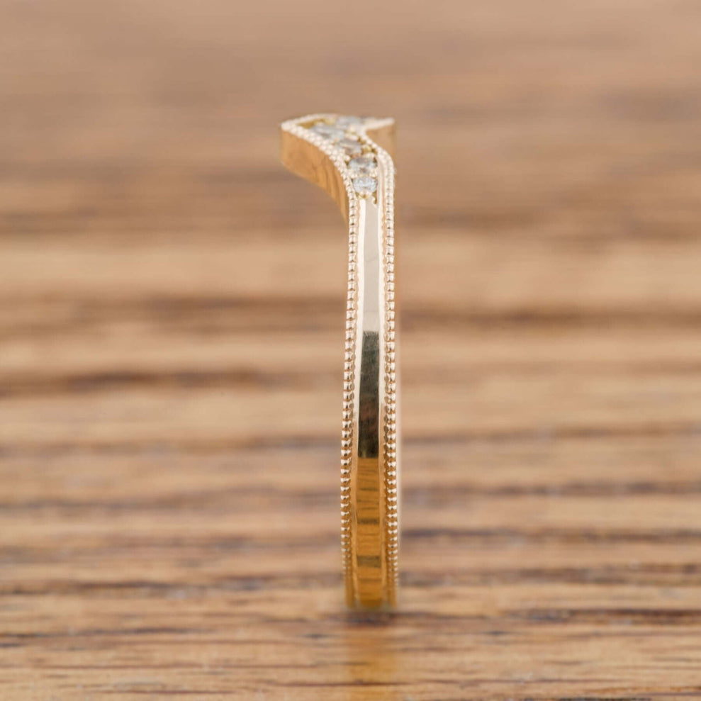 Profile view of 14k yellow gold chevron wedding ring with millgrain edge