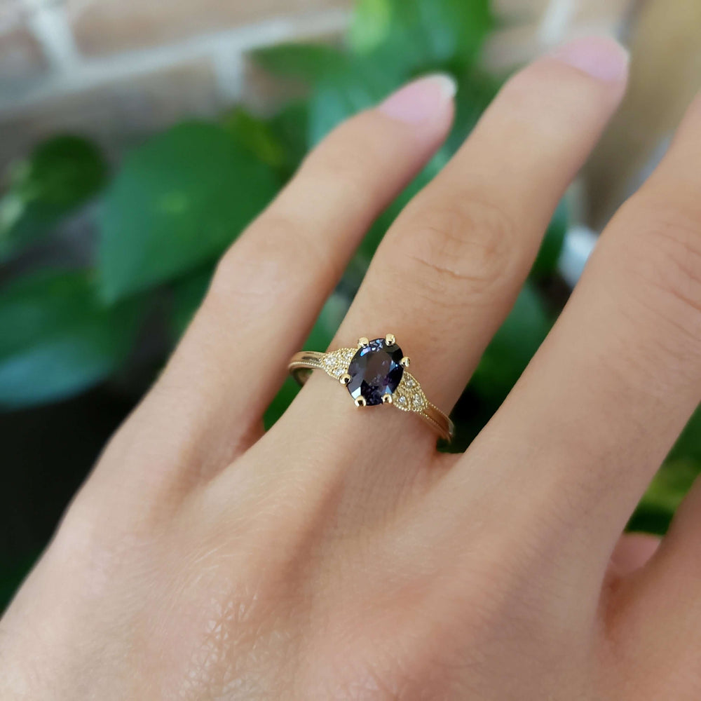 Purple sapphire and diamond yellow gold engagement ring worn on hand