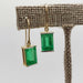 Rectangular emerald dangle earrings in 14kt yellow gold on display stand