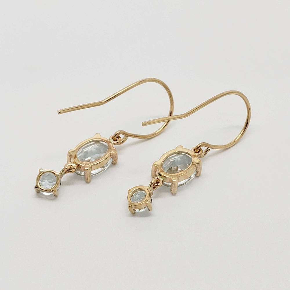Back view of 14kt yellow gold dangle earrings with oval and round aquamarine gemstones