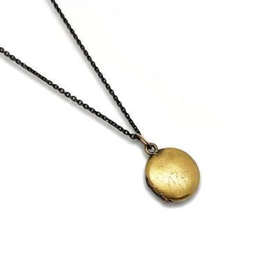 Reverse side of antique gold-toned round locket necklace on black chain