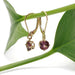 14kt yellow gold rhodolite garnet drop earrings displayed on a green leaf