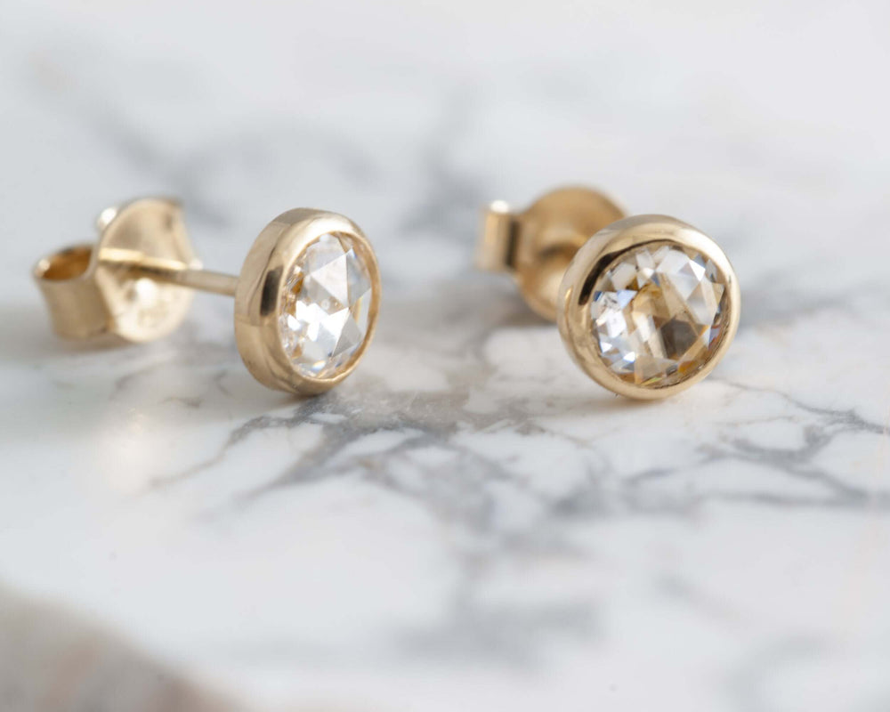 Rose cut moissanite earrings in 14kt yellow gold resting on marble