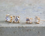Rose cut moonstone stud earrings in 14kt yellow gold, two sizes, on stone surface
