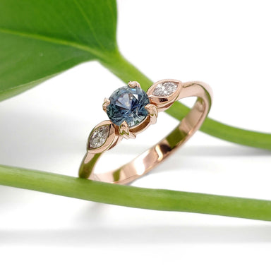 Handcrafted rose gold Montana sapphire and marquise diamond ring with leaf in background
