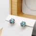 Blue zircon stud earrings in rose gold displayed on a white earring holder with cedar box