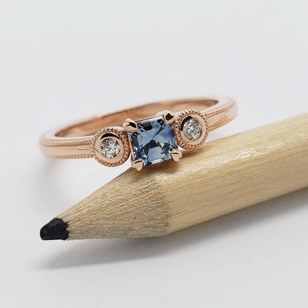 Rose gold engagement ring with blue asscher cut Montana sapphire and bezel set diamonds