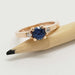 Rose gold engagement ring with blue Montana sapphire and diamonds, shown on a pencil