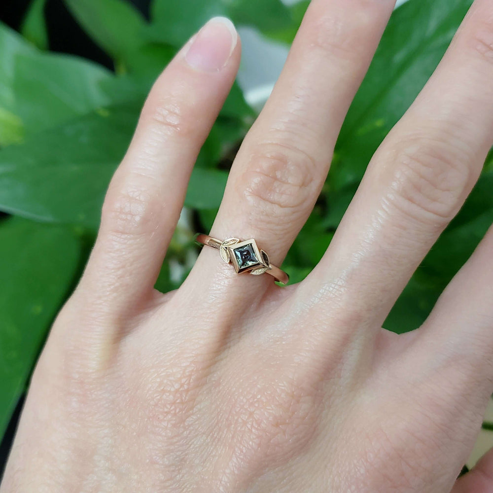 Rose gold green sapphire engagement ring with leafy setting shown on hand
