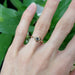 Rose gold green sapphire engagement ring with leafy setting shown on hand