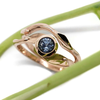 14kt rose gold leaf and twig wedding ring stacked with a blue gemstone engagement ring