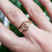 Rose gold leaf and twig wedding ring paired with a round diamond engagement ring on hand