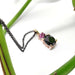 Handcrafted rose gold pendant with black spinel and pink sapphire beside green stem