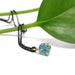 Round blue zircon pendant in 14kt yellow gold on black chain, styled with green leaf