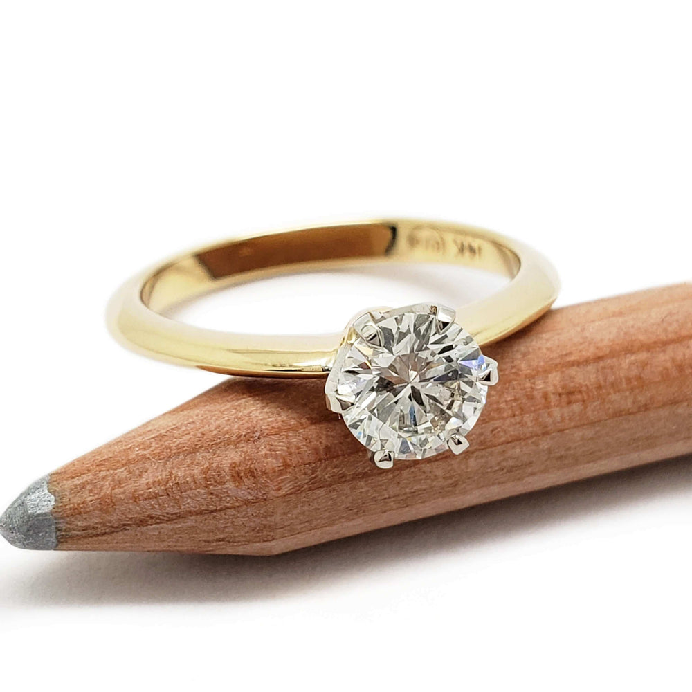 Round brilliant diamond solitaire ring in yellow gold with white gold prongs, on pencil