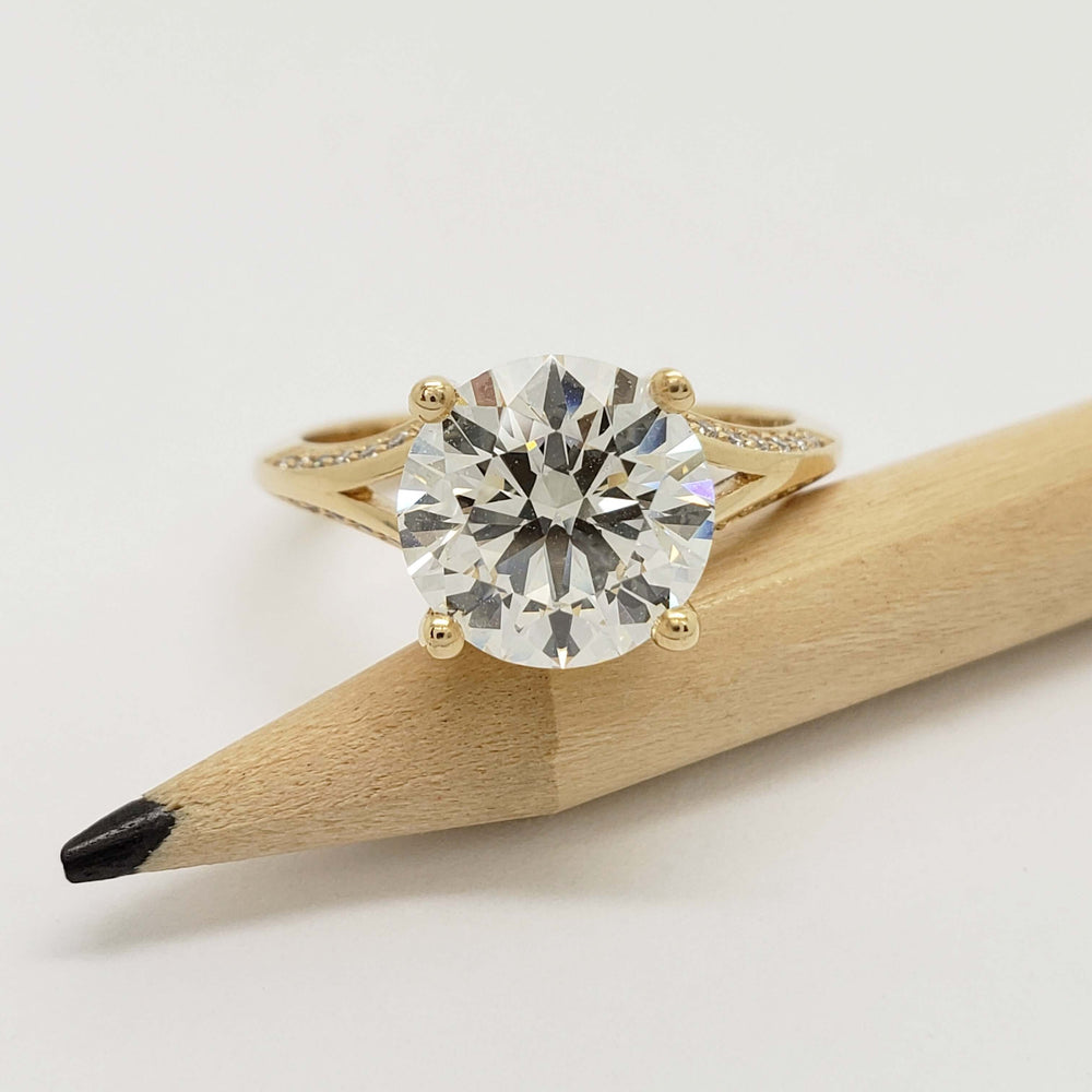 Round brilliant lab diamond engagement ring in yellow gold, shown next to a pencil for scale