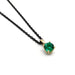 Round lab-grown emerald pendant in 14kt yellow gold on a black chain, angled view