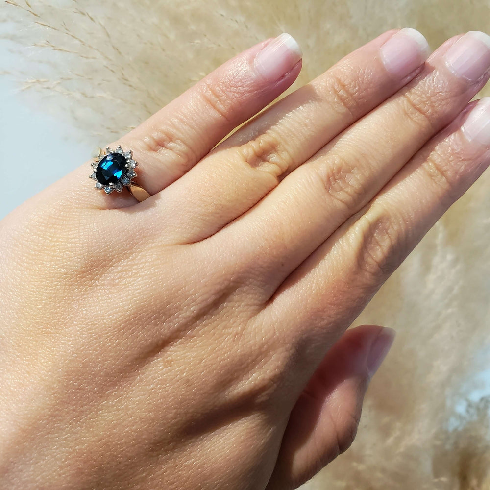 Sapphire and diamond halo ring in yellow and white gold shown on hand