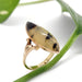 Side angled view of marquise dendritic agate set in detailed 10kt yellow gold ring against a leaf
