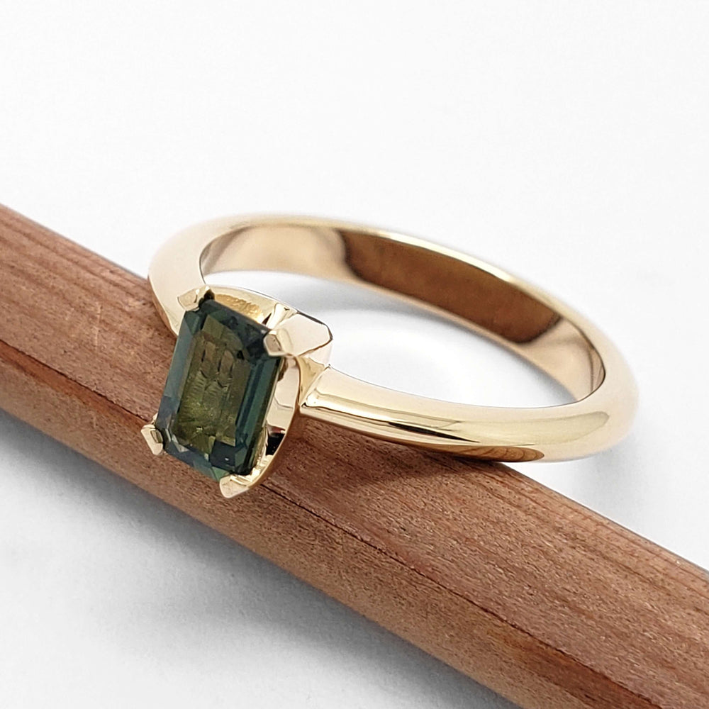 Side angle of 14kt yellow gold ring with emerald cut green Tanzanian sapphire on pencil