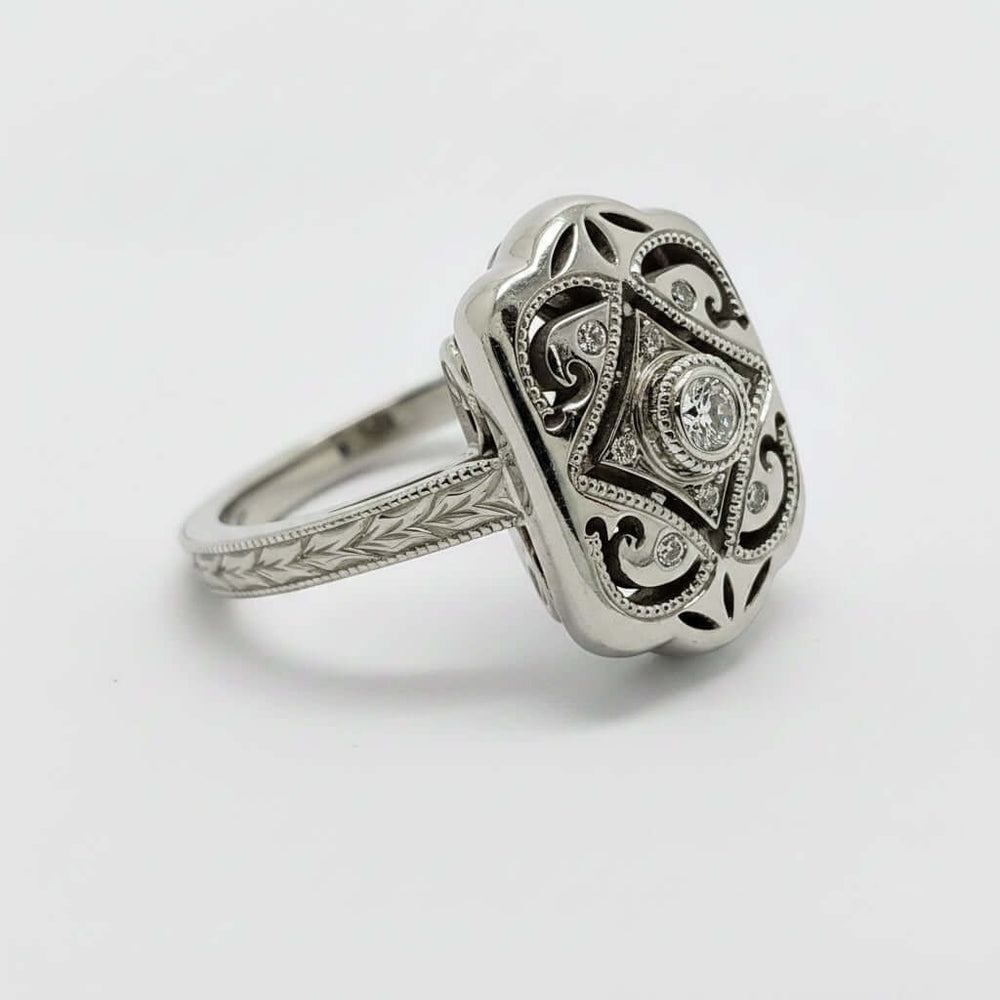 Side angle of white gold Edwardian engagement ring with diamond center and ornate engraving