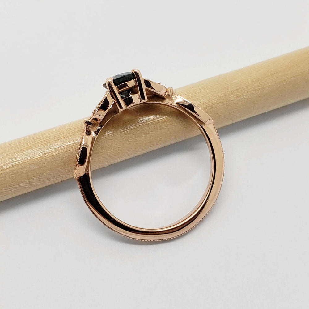 Side profile of 14k rose gold ring with teal sapphire and diamond leaf details