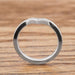 Side profile of 14k white gold chevron wedding band with millgrain edge on wood surface