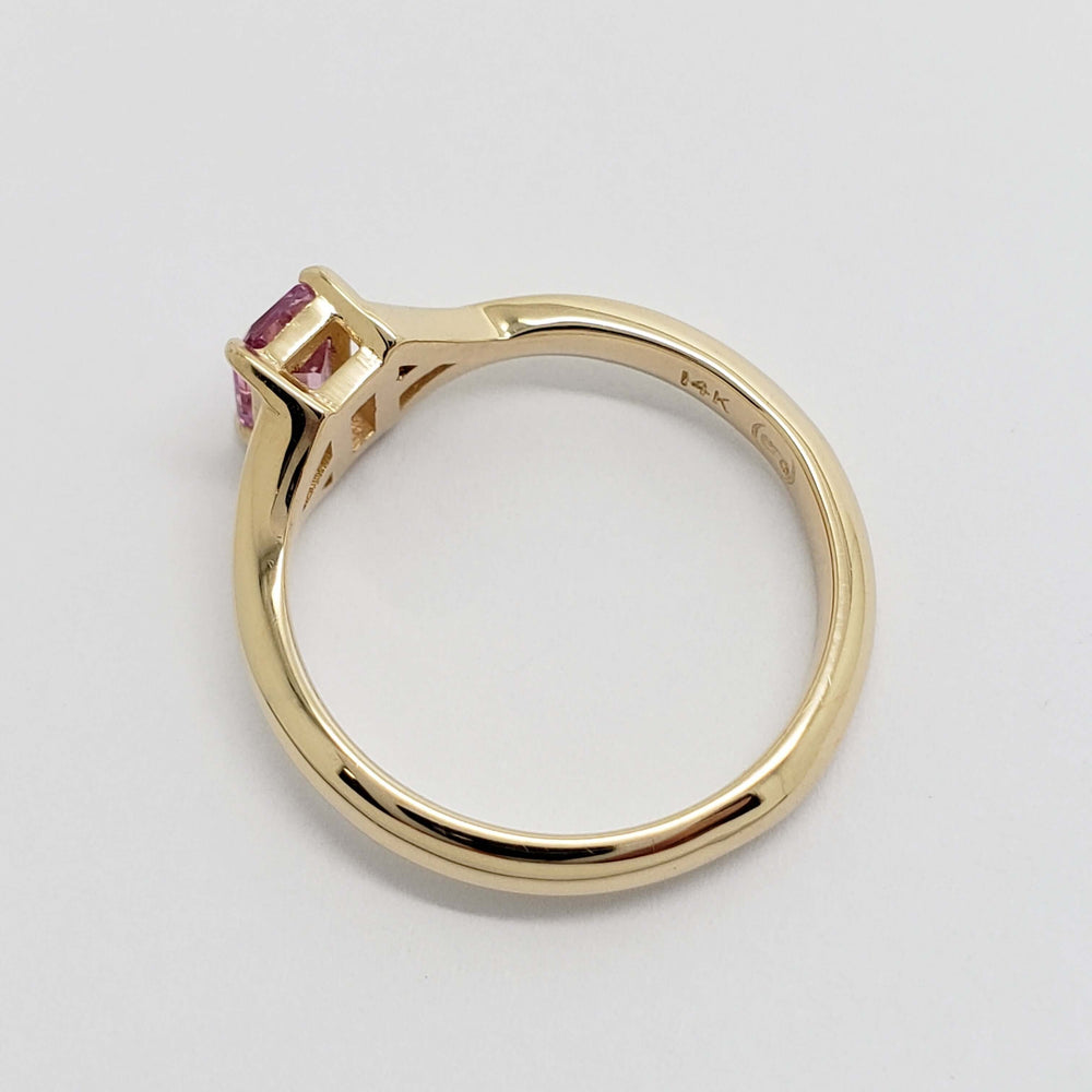 Side view of 14k yellow gold ring showing pink sapphire and hallmark