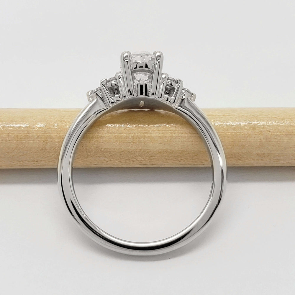 Side view of 14kt white gold oval lab diamond ring with accent stones on a pencil