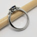 Side profile of 14kt white gold ring with blue emerald cut sapphire and pear diamonds